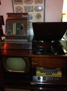 Clockwise from top left: cash register, record player, television, and radio, all very vintage.